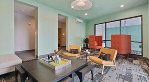 A modern lounge area with a dark wooden table, two orange armchairs, and a sofa. - Landing | Chic 1BD, Clubhouse, Gym (Durham)
