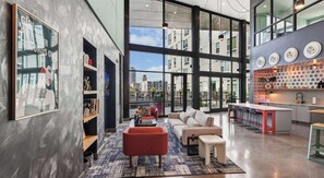 A modern interior with a seating area, a kitchen, and large windows offering city views. - Landing | Spectacular 1BD, Clubhouse, Gym (Durham)