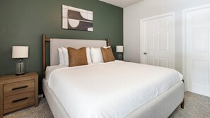 A neatly made bed with a headboard, two bedside tables with lamps, a door, and a wall-mounted abstract art piece. - Landing | Beautiful 2BD, Gym, Courtyard (Allen)