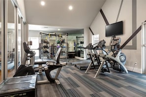 A gym with cardio machines, weightlifting equipment, and a mirrored wall. - Landing | Stunning 2BD, Courtyard, Gym (Allen)
