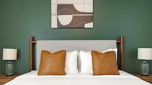 Une chambre d’hôtel avec un lit, deux lampes de chevet, une œuvre d’art murale et un mur vert.