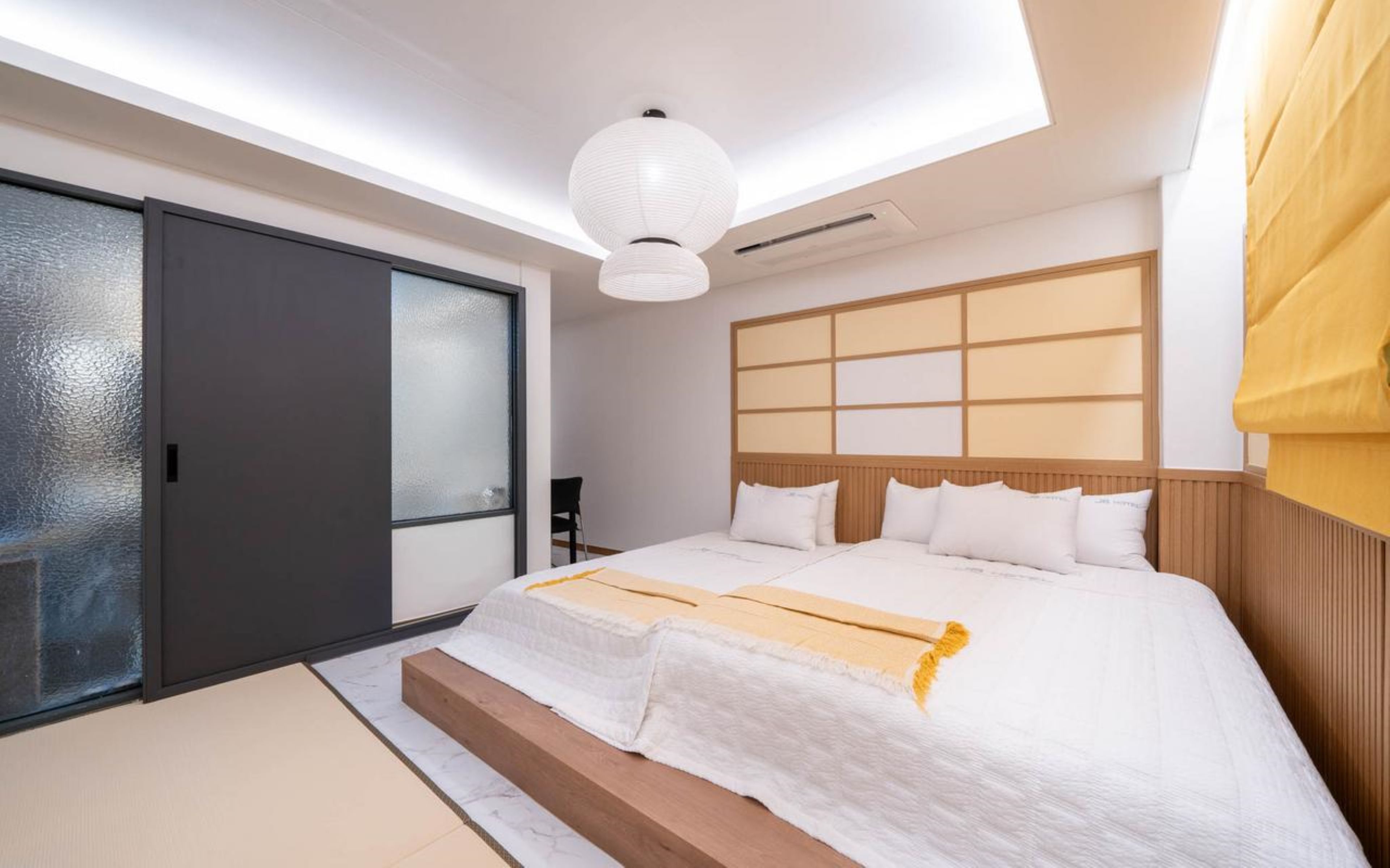 Un dormitorio moderno con una cama grande, puerta corredera de vidrio y una lámpara en el techo.
