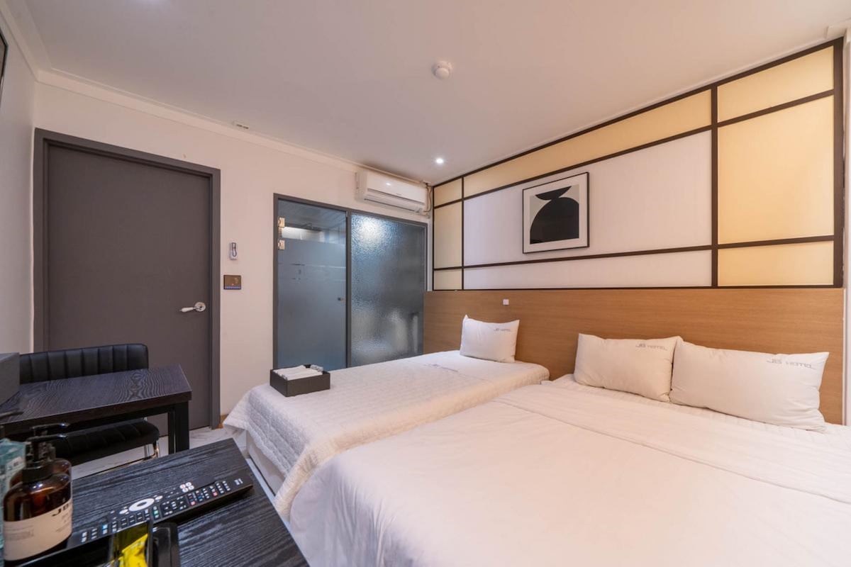 Una habitació d'hotel amb dos llits, una taula i una cadira.