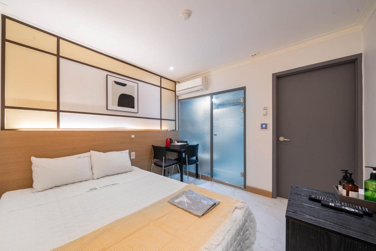 Una habitación de hotel con cama, mesita de noche y escritorio con sillas.