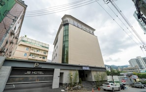 Un hotel amb un disseny modern, un aparcament i una escala que condueix a l'entrada.