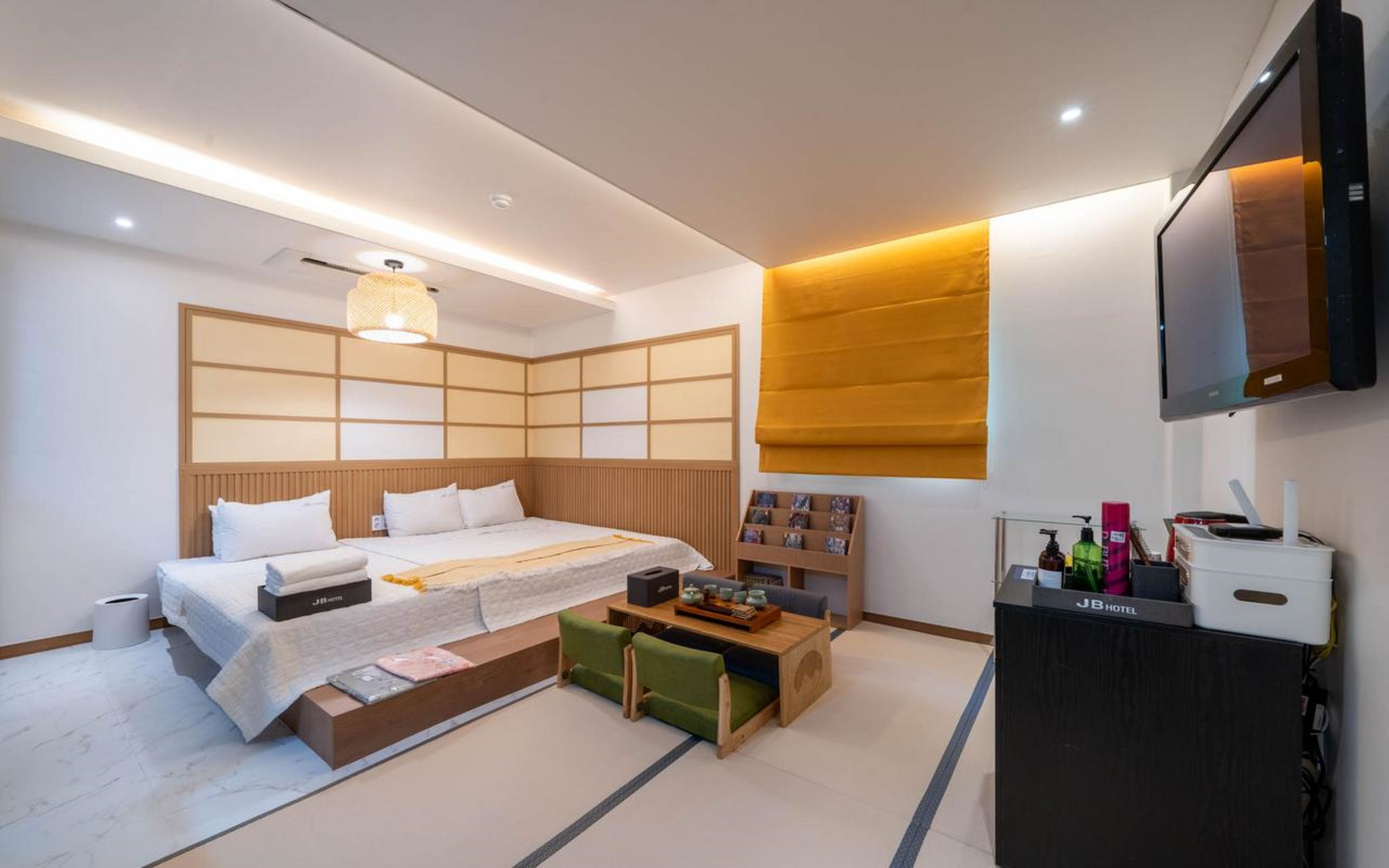 Una habitación de hotel moderna con una cama, una mesita de noche y un televisor montado en la pared.