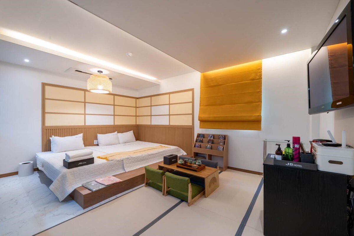 Una habitación de hotel moderna con una cama, una mesita de noche y un televisor montado en la pared.