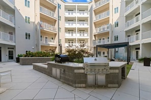 Une cour avec un barbecue et un espace détente, le tout entouré d’immeubles d’appartements.
