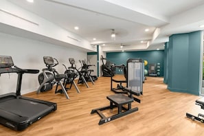 A gym with cardio machines, a weight bench, and a wall-mounted exercise machine. - Landing | Chic 1BD, Gym, Courtyard (Concord)