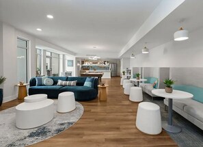 Un espacio habitable moderno con un sofá, otomanas y una cocina al fondo.
