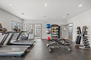 A gym with treadmills, a stationary bike, a bench press, and a rack of dumbbells. - Landing | Chic 2BD, Gym, Clubhouse (Chattanooga)