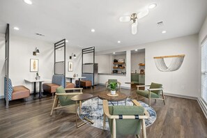 A modern living room with a round coffee table, seating area, and a kitchen in the background. - Landing | Chic 2BD, Gym, Clubhouse (Chattanooga)