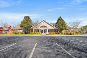 A building with a central entrance, parking lot, and a playground with a red slide. - Landing | Stylish 2BD, Clubhouse, Gym (Chattanooga)
