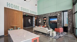 En moderne lobby med en marmorreception, en sofa og et tv, der viser et bybillede.