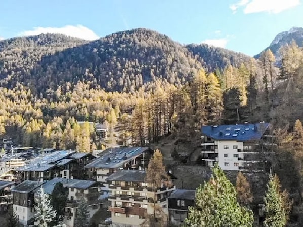 A mountainous area with a cluster of buildings, some with flat roofs and others with sloped roofs, surrounded by trees and hills. - Tuftra Penthouse 4BR Zermatt by Interhome (Zermatt)