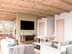 A modern living room with a large flat-screen TV, a wooden ceiling, and a sofa set. - Tuftra Penthouse 4BR Zermatt by Interhome (Zermatt)
