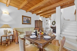 Zona de menjador amb taula de fusta preparada per a dinar, un sofà i una escala.