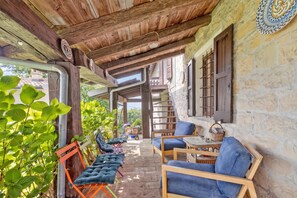 Un espace extérieur abrité, aménagé avec du mobilier en bois et un mur en pierre.