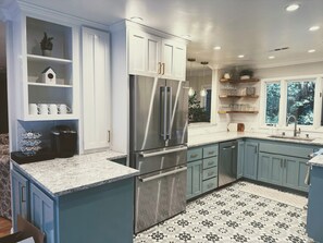 Una cocina moderna con un refrigerador de acero inoxidable, gabinetes azules y un piso de baldosas con diseño.