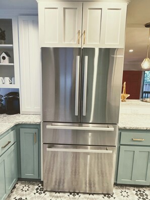 A stainless steel refrigerator with two doors and a freezer drawer, situated in a kitchen with teal cabinetry and a patterned tile floor. - Lafayette Hills 3BR Private Family Getaway Near Walnut Creek (Lafayette)