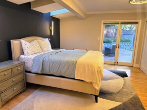 Un dormitorio con cama, mesita de noche y vistas a través de un ventanal.