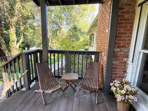 A wooden deck with two chairs and a table, a brick wall, and a window. - Lafayette Hills 3BR Private Family Getaway Near Walnut Creek (Lafayette)