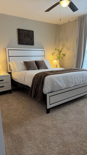 A bedroom with a bed, nightstands, a ceiling fan, a wall-mounted artwork, and a potted plant. - Walk to Shops & Restaurants - 6BR in Heart of Downtown Lexington (Lexington)