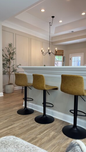 A bar area with three stools, a chandelier, and a potted plant. - Walk to Shops & Restaurants - 6BR in Heart of Downtown Lexington (Lexington)