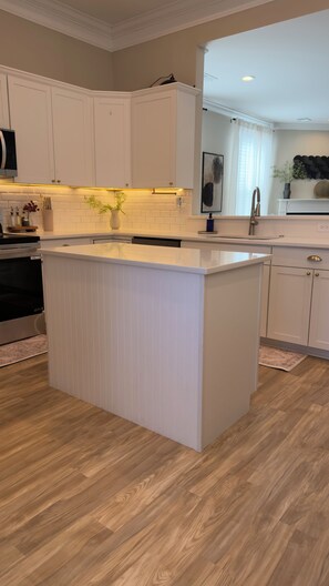 Une cuisine moderne avec des meubles blancs, un îlot central et un plancher en bois.