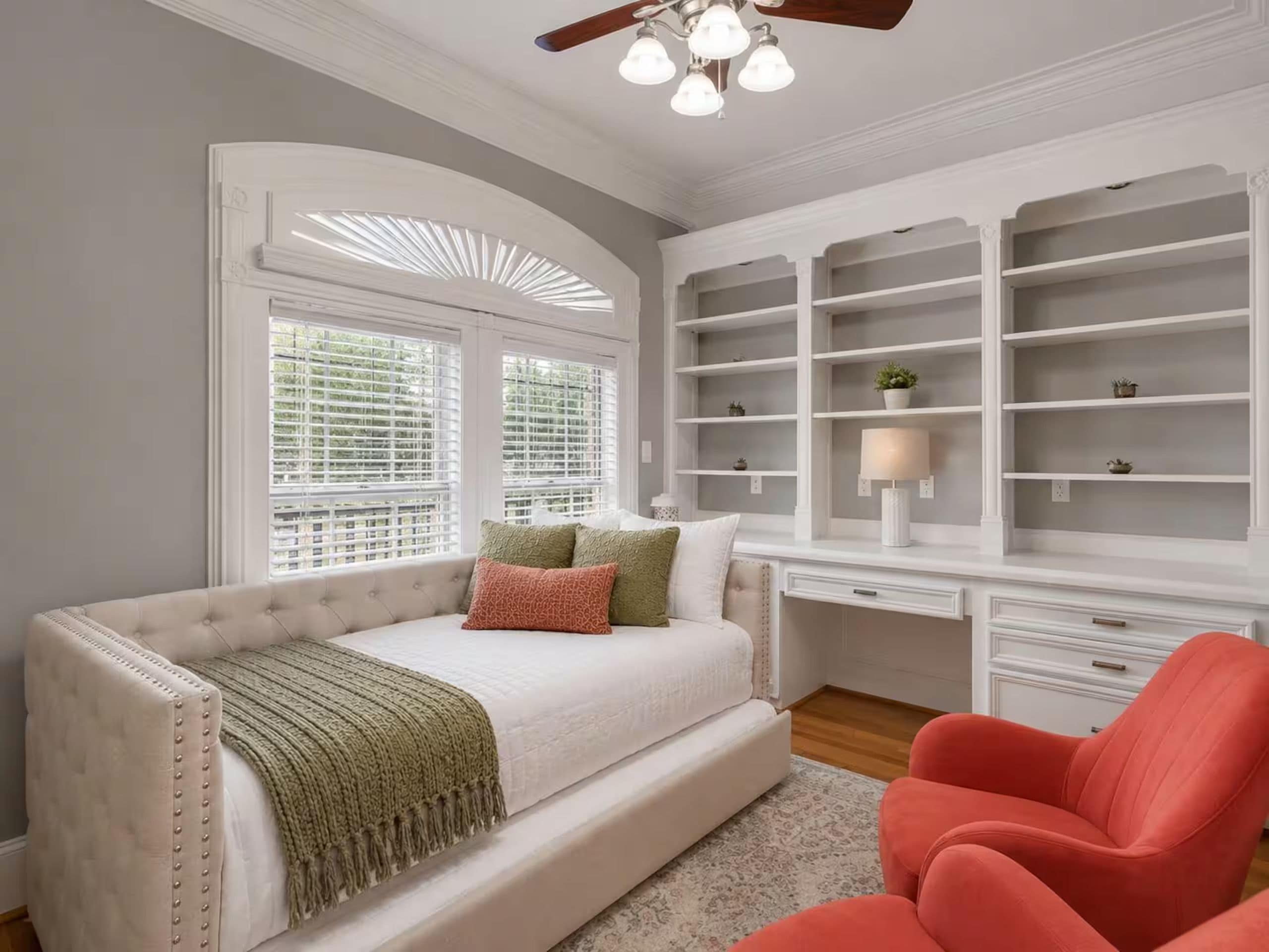 A bedroom with a bed, a desk, and built-in shelving.