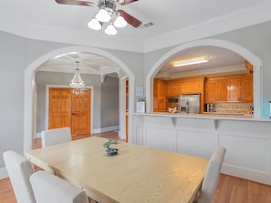 A dining area with a wooden table and chairs, a chandelier, and a kitchen with wooden cabinets and appliances. - Spacious Houston Retreat Sleeps 26 (Houston)