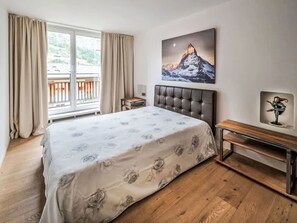 A bedroom with a bed, a nightstand, a painting, and a window with curtains. - 4BR Clémenceau Duplex Penthouse by Interhome (Verbier)