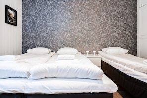 Une chambre d’hôtel avec deux lits, une table de chevet et un mur orné d’un motif floral.