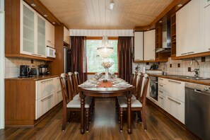 A dining area with a round table set for four, surrounded by wooden chairs. - Ounasrinne 3BR House, Sauna By Lapland Host (Rovaniemi)