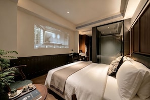 A hotel room with a bed, a desk, a chair, a plant, and a projection screen on the wall. - Relanding Hotel Zhuhai Gongbei Port (zhuhai)