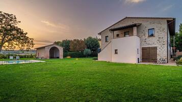 A modern house with a stone facade, a large lawn, and a swimming pool.
