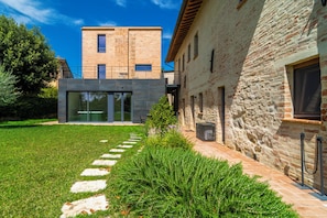 Un edificio moderno con fachada de piedra, entrada de cristal y césped cuidado con piedras para caminar.