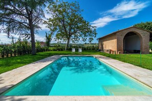 Una piscina rectangular con superficie de agua azul cristalina, rodeada por un deck pavimentado.
