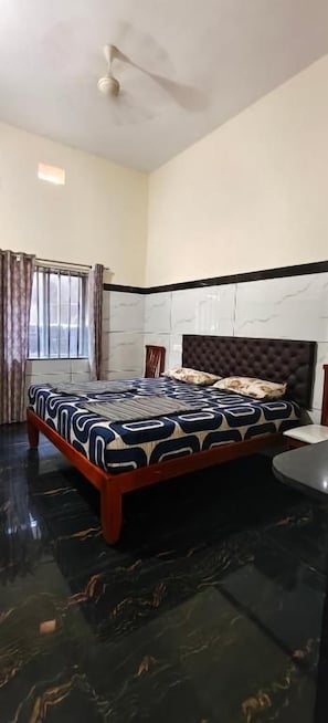 Un dormitorio con cama, ventilador de techo y ventana con cortinas.