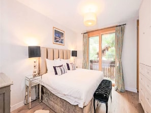 A bedroom with a bed, bedside tables, a bench, a window with curtains, and a wall-mounted picture. - Crux Penthouse by Interhome (Sankt Anton am Arlberg)