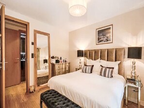A hotel room with a large bed, a bedside table, a mirror, a wardrobe, and a painting on the wall. - Crux Penthouse by Interhome (Sankt Anton am Arlberg)