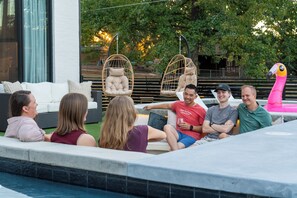 A group of people relaxing by a poolside with wicker chairs and a pink flamingo decoration. - Luxe | Pool, Sauna, & Karaoke | Sleeps 16 (Garland County)