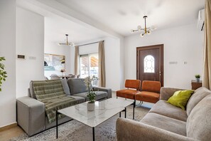A modern living room with a sofa, armchairs, a coffee table, and a dining area. - Gordonos – Modern 3Bed Apartment with Large Garden (Limassol)