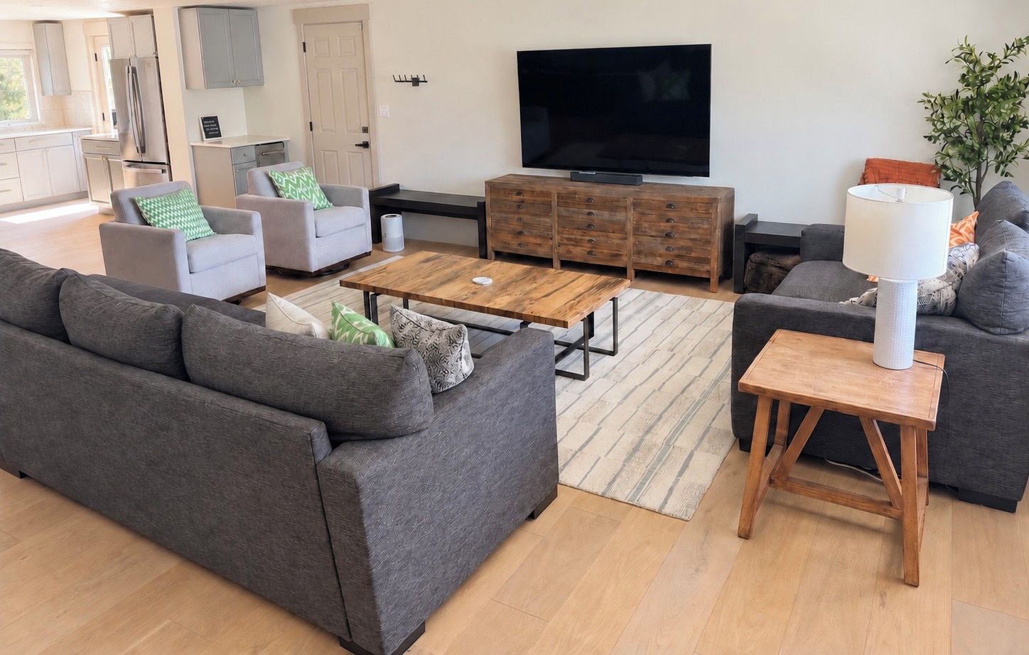 Ein modernes Wohnzimmer mit einem grauen Sofa, einem Holztisch, einem Fernseher und einer Lampe.