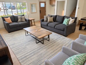 A modern living room with two grey sofas, a wooden coffee table, and a striped rug. - Newly Renovated Riverwoods Retreat — 4BR, 3BA (Orem)