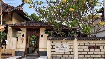 Un bâtiment traditionnel avec un toit en tuiles et une enseigne indiquant « Griya Nusa Homestay ».