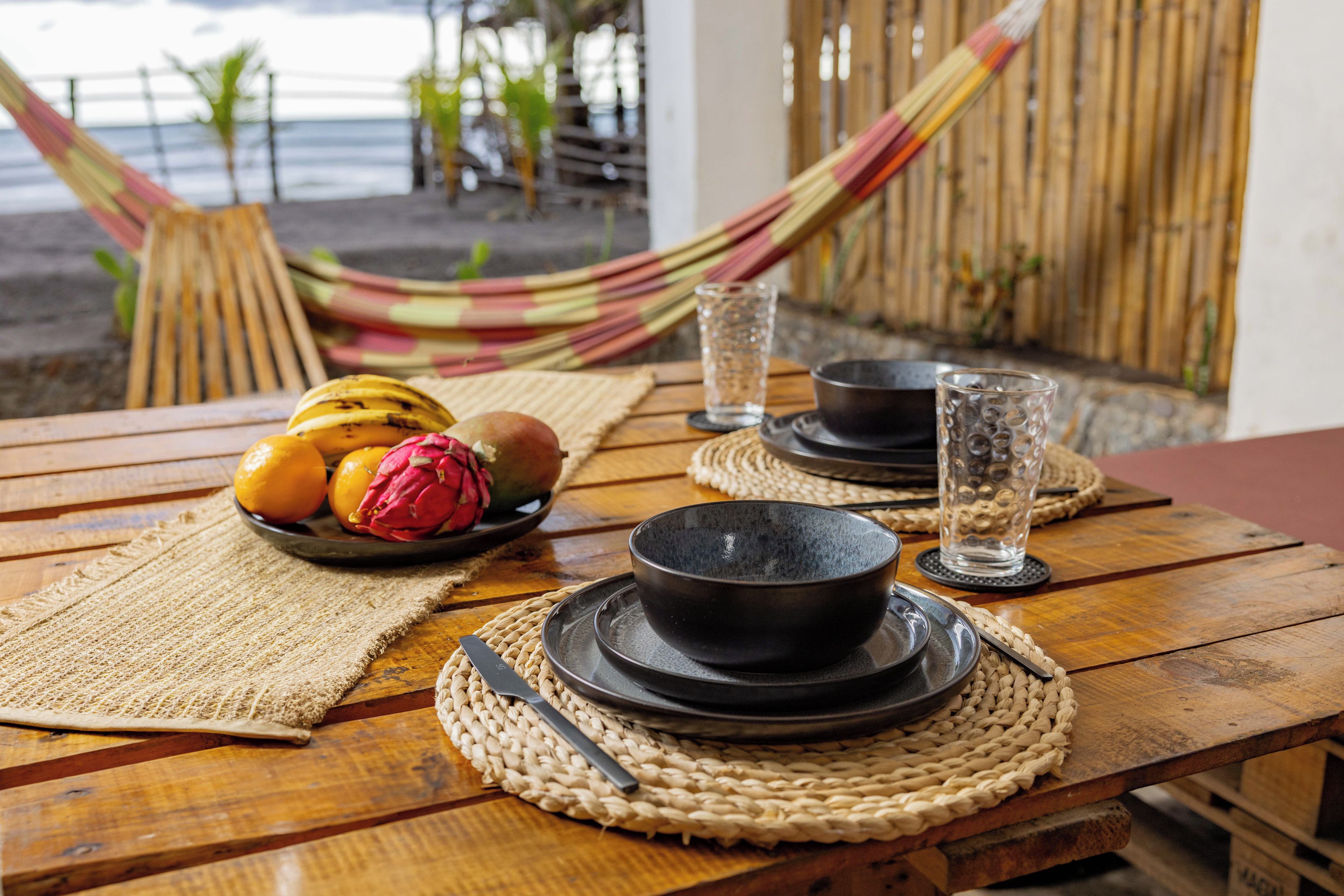 A wooden table with a plate of fruit, a bowl, and a glass of water.
