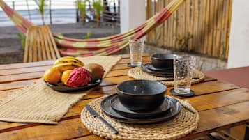 A wooden table with a plate of fruit, a bowl, and a glass of water.
