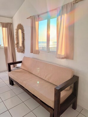 Una habitación con sofá, espejo y vista al mar.