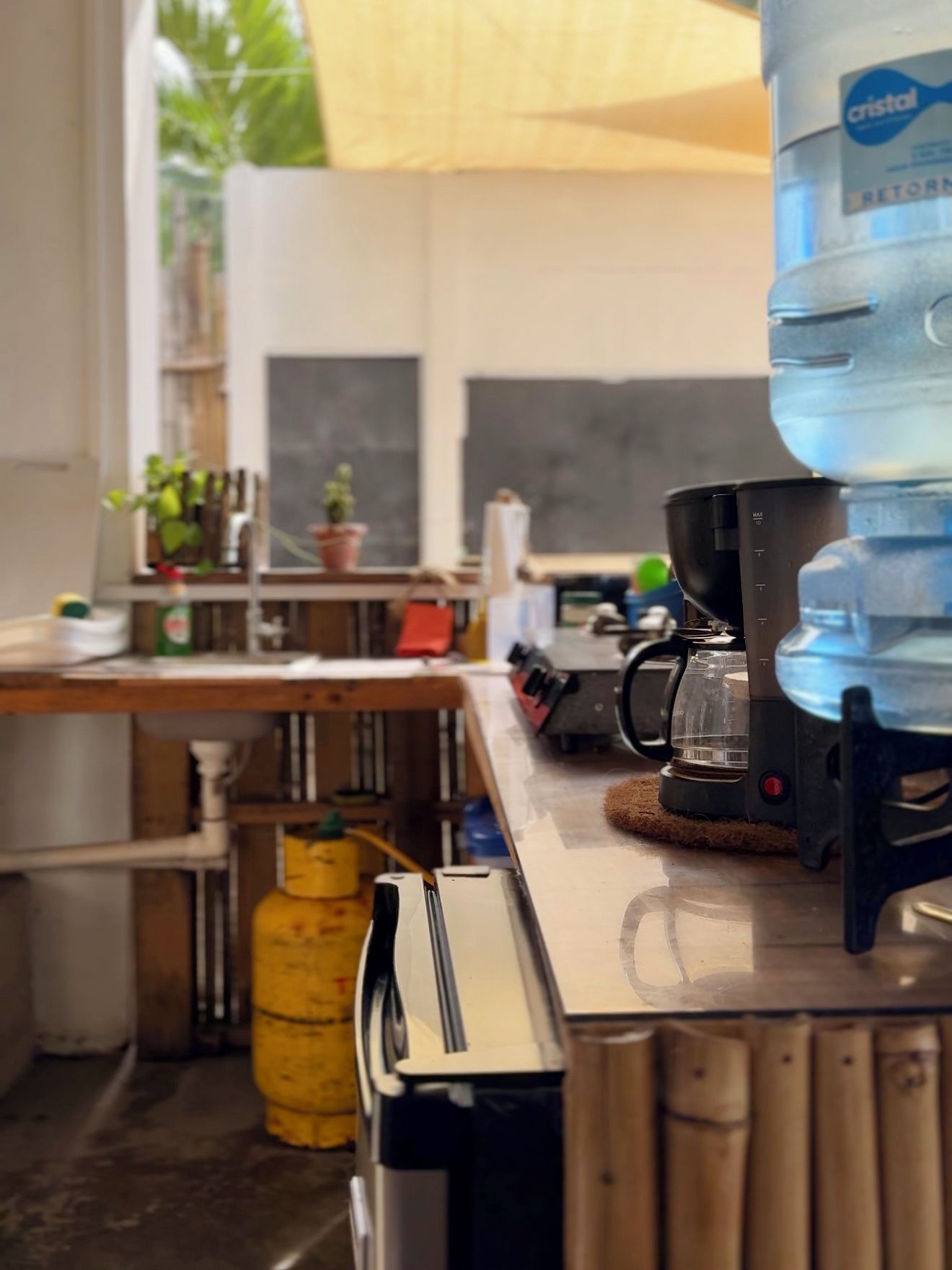 A kitchen with a water dispenser, coffee maker, and a yellow gas cylinder.